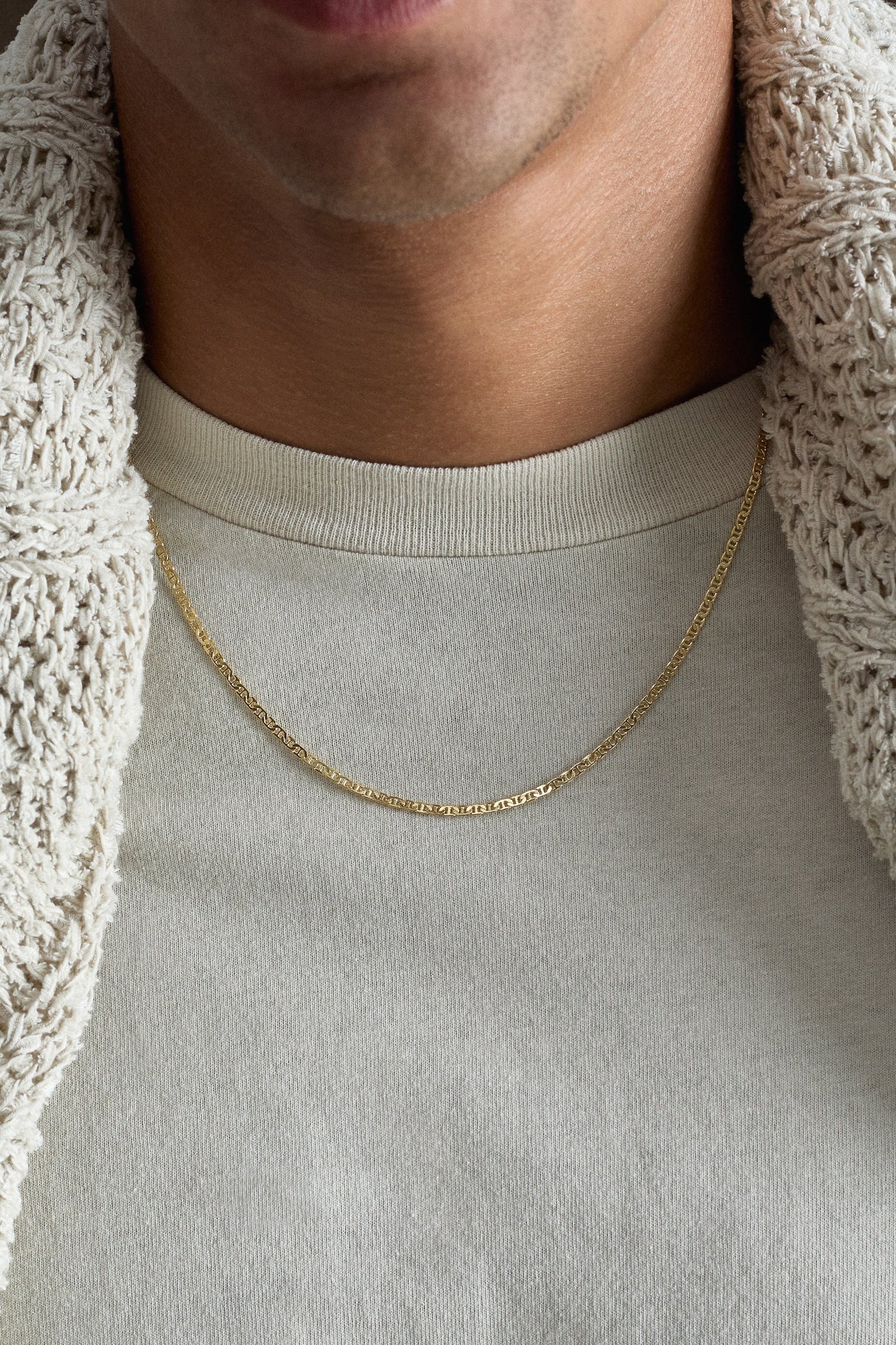 Gold necklace worn by a person with a neutral background