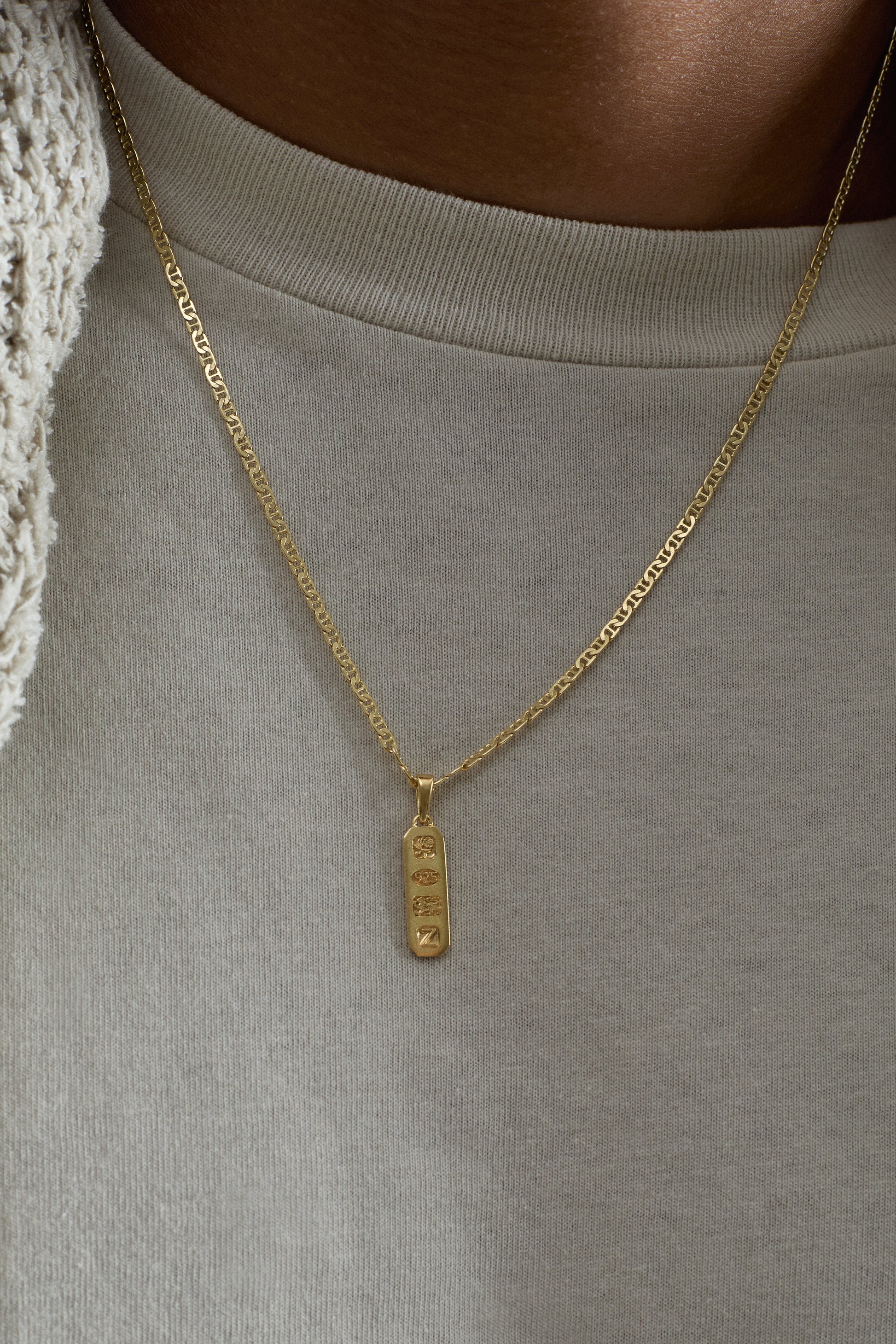 Gold necklace with a pendant worn by a person in a neutral setting